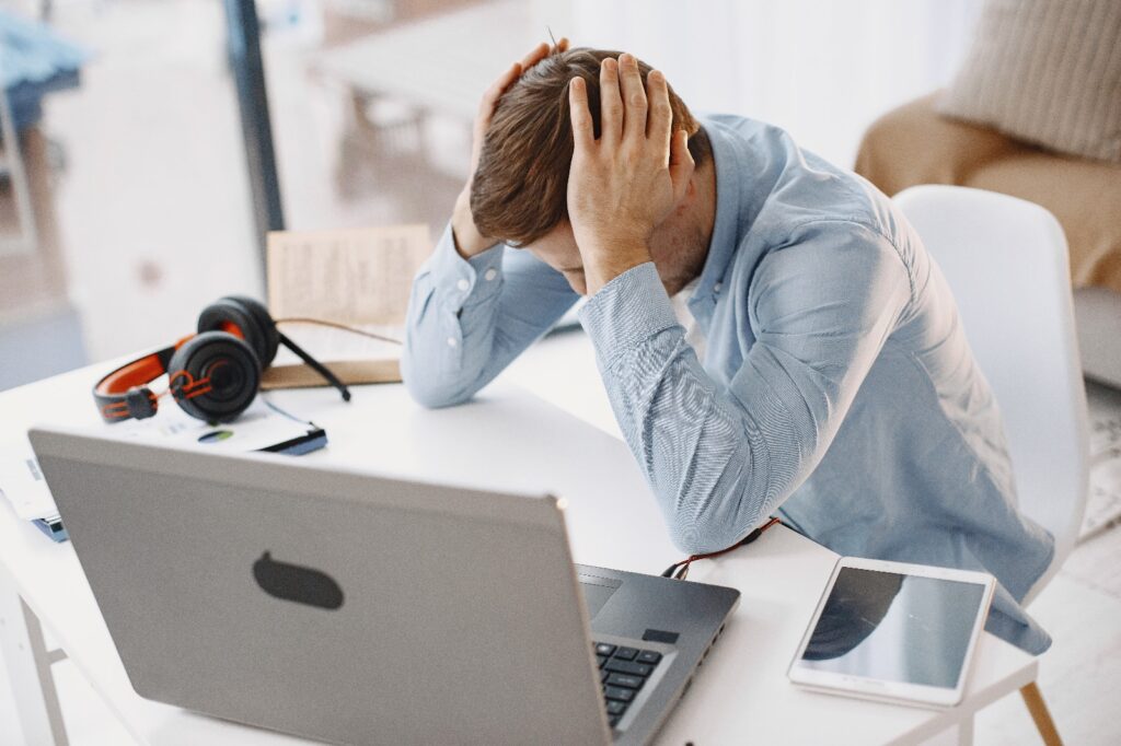 Personne devant un ordinateur qui se tient la tête